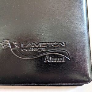 Lambton College Alumni black folder. Pockets inside.